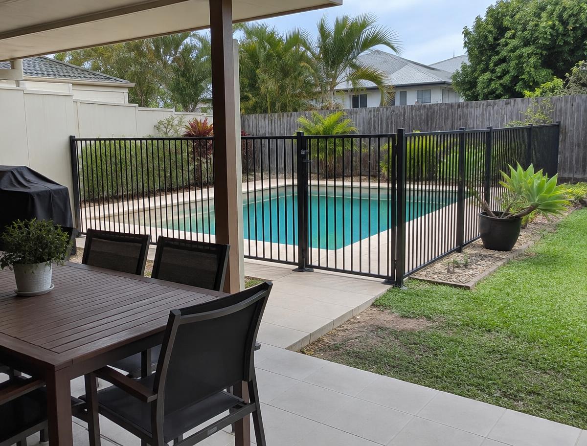 A fenced swimming pool and patio in a home backyard